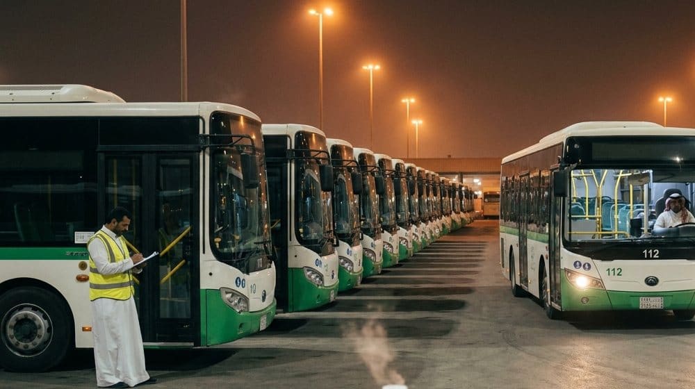 مشرف يحمل لوحاً بجانب صف من الحافلات في مستودع ليلاً