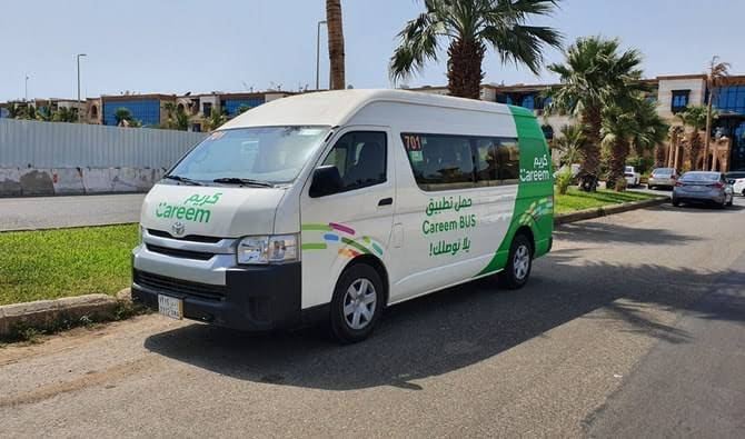 A white and green passenger minibus parked on a city street